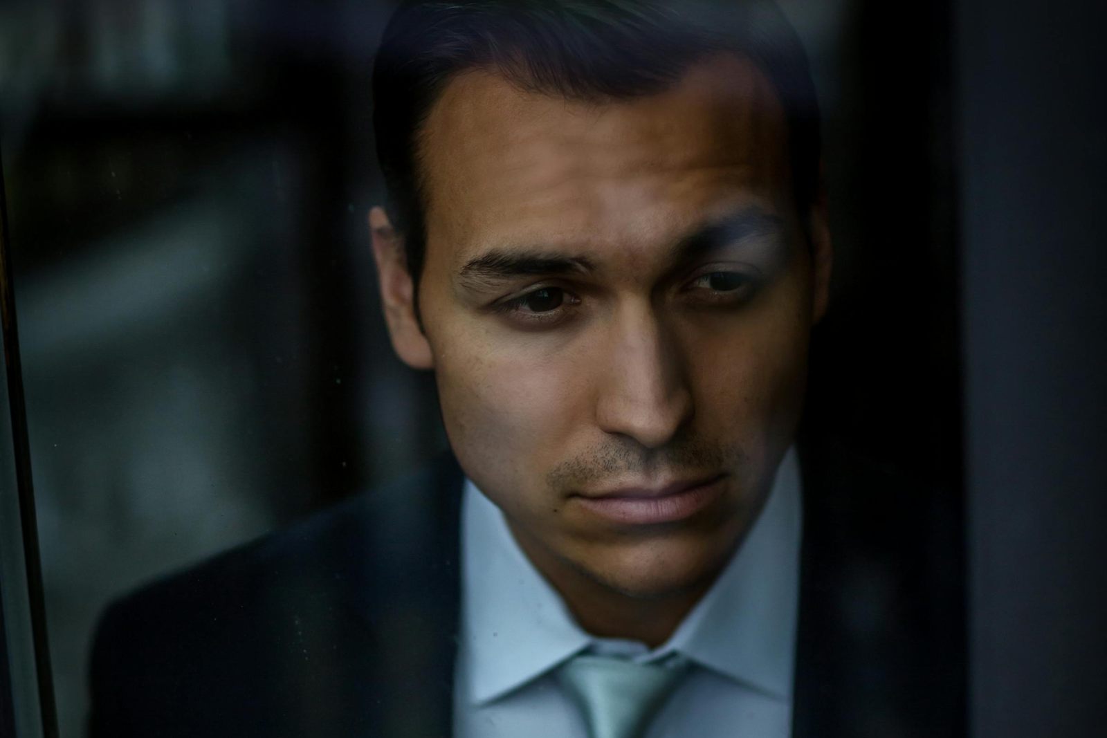 Portrait pensif d'un dirigeant en costume sombre regardant par la fenêtre, illustration de l'incarnation humaine du discours d'entreprise, ce qu'aucune intelligence artificielle ne peut produire